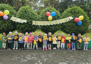 Dzieci stoją na tarasie przedszkolnym, pozują do zdjęcia grupowego