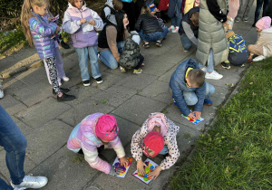dzieci wykonują „mural” malując kleksami farby na kartce zamkniętej w woreczku strunowym