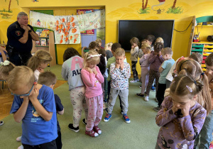 dzieci w parach stojąc plecami do siebie pokazują pozycję „drzewo”