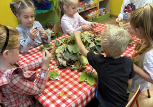 dzieci nawlekają na drucik kreatywny liście tworząc gąsienicę