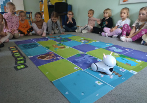 dzieci programują trasę jaką ma pokonać robot na macie do kodowania
