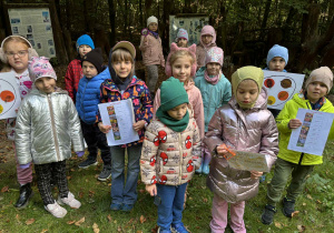 dzieci stojąc prezentują wykonaną „paletę barw” z naklejonymi na niej roślinami,