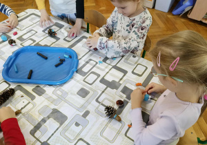 dzieci tworzą z kasztanów i materiału przyrodniczego „kasztanowe stworki”