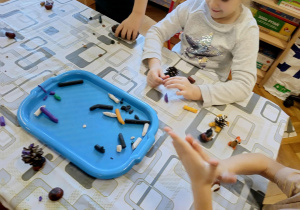 dzieci tworzą z kasztanów i materiału przyrodniczego „kasztanowe stworki”