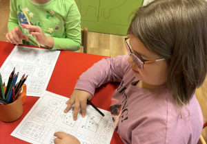 dzieci siedzą przy stolikach i projektują swoje osiedle,