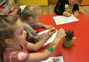 dzieci siedzą przy stolikach i projektują swoje osiedle,