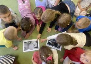 dzieci siedzą na dywanie oglądając zdjęcia