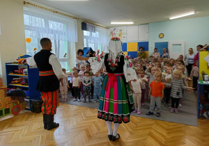 tancerze prezentują tańce ludowe, dzieci siedzą w sali przyglądając się ich tanecznym popisom