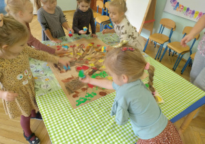 dzieci przy stolikach wykonują prace plastyczna