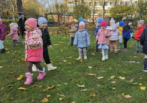 Dzieci w ogrodzie ustawione w rozsypce ćwiczą chwyt karate