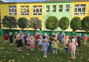 Dzieci w ogrodzie ustawione w rozsypce ćwiczą chwyt karate