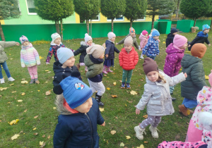 Dzieci w ogrodzie ustawione w rozsypce ćwiczą chwyt karate