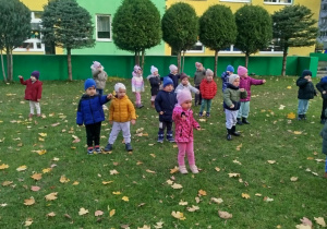 Dzieci w ogrodzie ustawione w rozsypce ćwiczą chwyt karate