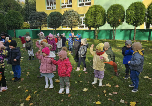 Dzieci w ogrodzie ustawione w rozsypce ćwiczą chwyt karate