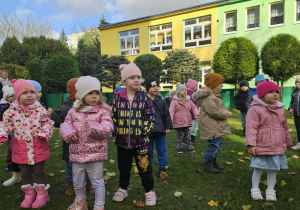 Dzieci w ogrodzie ustawione w rozsypce ćwiczą chwyt karate