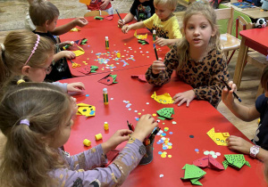 dzieci składają papier origami tworząc żaby, serca i pieski