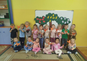 Dzieci z grupy pomarańczowej pozują do zdjęcia grupowego z wykonanymi techniką origami liskami.