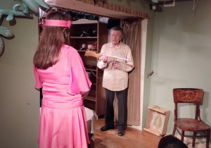 Aktorzy stoją na scenie i prezentują rekwizyty które wykorzystane były w spektaklu.