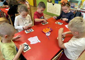 dzieci wyklejają pomarańczową bibułą dynię