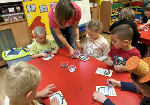 dzieci wyklejają szablon dyni nasionami dyni