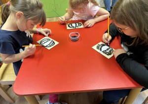 dzieci wyklejają szablon dyni nasionami dyni