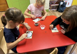 dzieci wyklejają szablon dyni nasionami dyni