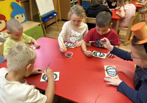 dzieci wyklejają szablon dyni nasionami dyni