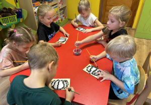 dzieci wyklejają szablon dyni nasionami dyni