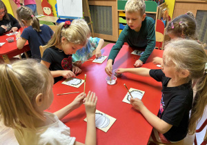 dzieci wyklejają szablon dyni nasionami dyni