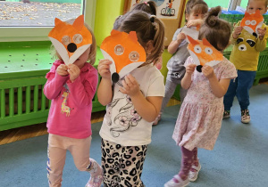 Dzieci z masķą liska chodzą po dywanie