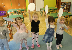 Dzieci podnoszą koła z papieru nad głowę.