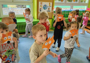 Dzieci z masķą liska chodzą po dywanie