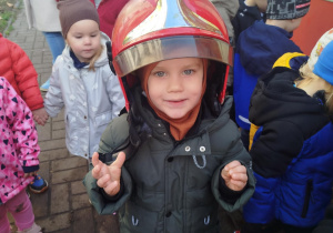 Dzieci przymierzają kaski strażackie.