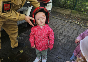 Dzieci przymierzają kaski strażackie.