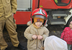Dzieci przymierzają kaski strażackie.
