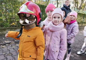 Dzieci przymierzają kaski strażackie.