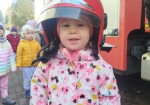 Dzieci przymierzają kaski strażackie.
