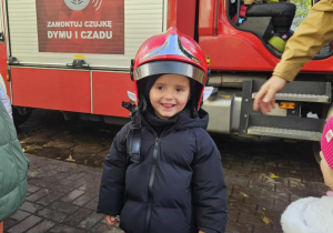 Dzieci przymierzają kaski strażackie.