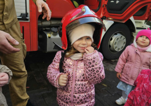 Dzieci przymierzają kaski strażackie.