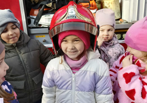 Dzieci przymierzają kaski strażackie.