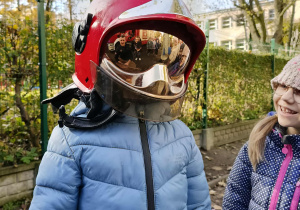 Dzieci przymierzają kaski strażackie.