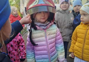 Dzieci przymierzają kaski strażackie.