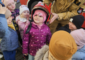 Dzieci przymierzają kaski strażackie.