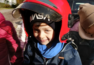 Dzieci przymierzają kaski strażackie.