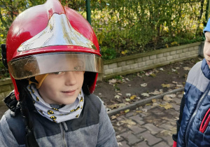 Dzieci przymierzają kaski strażackie.
