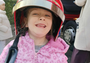 Dzieci przymierzają kaski strażackie.