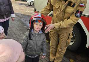 Dzieci przymierzają kaski strażackie.