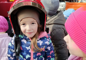 Dzieci przymierzają kaski strażackie.