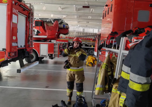 Strażak prezentuje gotowy ubiór na wyjazd do wezwania.