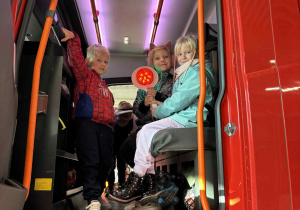 dzieci siedzą w kabinie wozu strażackiego